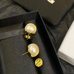 Gold-tone pearl stud earrings with hinged backs and small logo detail