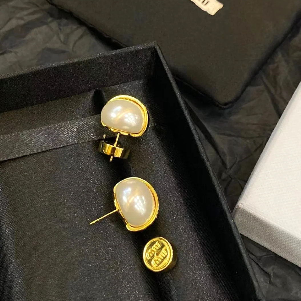Gold-tone pearl stud earrings with hinged backs and small logo detail