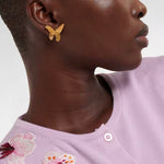 Gold butterfly earrings on ear, close-up view from side
