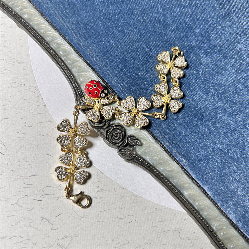 Gold-tone ladybug and clover charm bracelet with rose-like center charm and clasp
