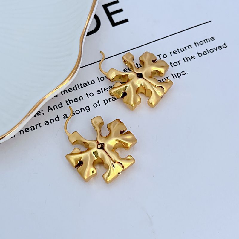Gold 3D logo metal hoop earrings, sculpted floral emblem near thin chain