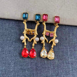 Clip-on earrings with gold branch design, blue and red crystals, and white pearls