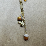 Gold pendant necklace with small squirrel charm, brown pinecone bead, and sparkle cap