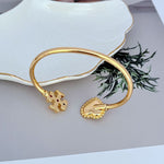 Gold open bangle close-up of heart clasp and mother-of-pearl heart charm