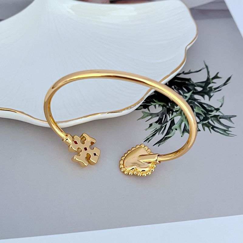 Gold open bangle close-up of heart clasp and mother-of-pearl heart charm