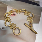 Goldfarbenes Blumenarmband mit klar funkelnden Steinen, Ring-Schließe und Stab-Anhänger