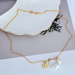 Baroque pearl logo pendant necklace with gold-tone chain and small charm detail