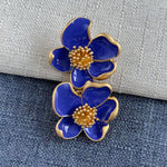 Deep blue enamel floral stud earrings with gold-tone petals and golden beaded details