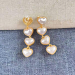White heart-shaped long drop earrings, five pearl hearts per side with gold-tone links
