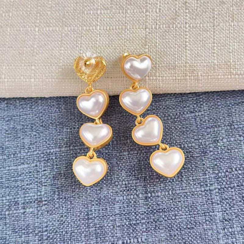 White heart-shaped long drop earrings, five pearl hearts per side with gold-tone links