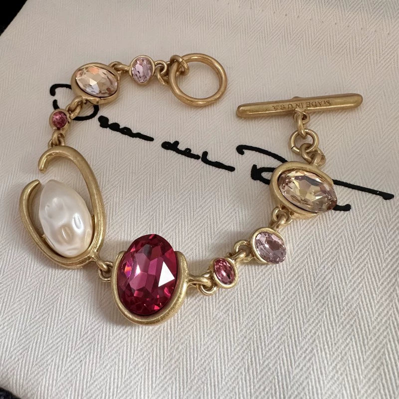 O-ring crystal pearl bracelet, gold tone with red oval center stone, pink crystals, pearl