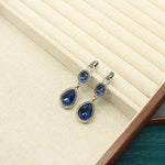 Silver teardrop pendant earrings with blue crystal stones, double-sided design.