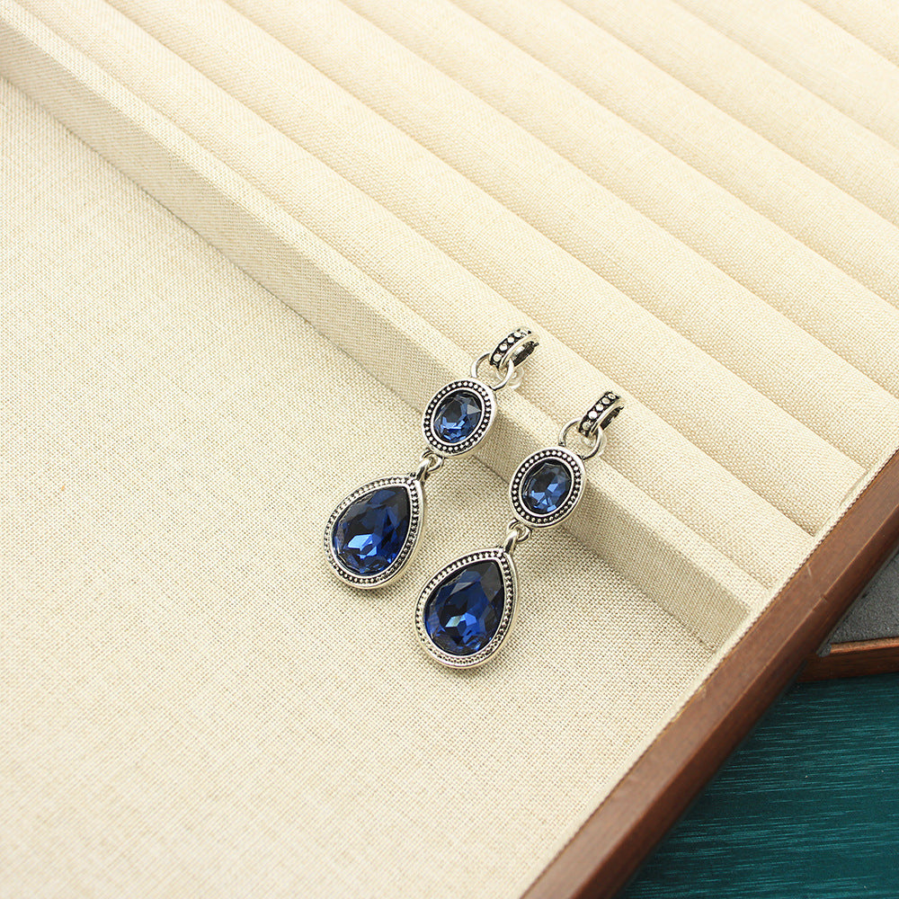 Silver teardrop pendant earrings with blue crystal stones, double-sided design.
