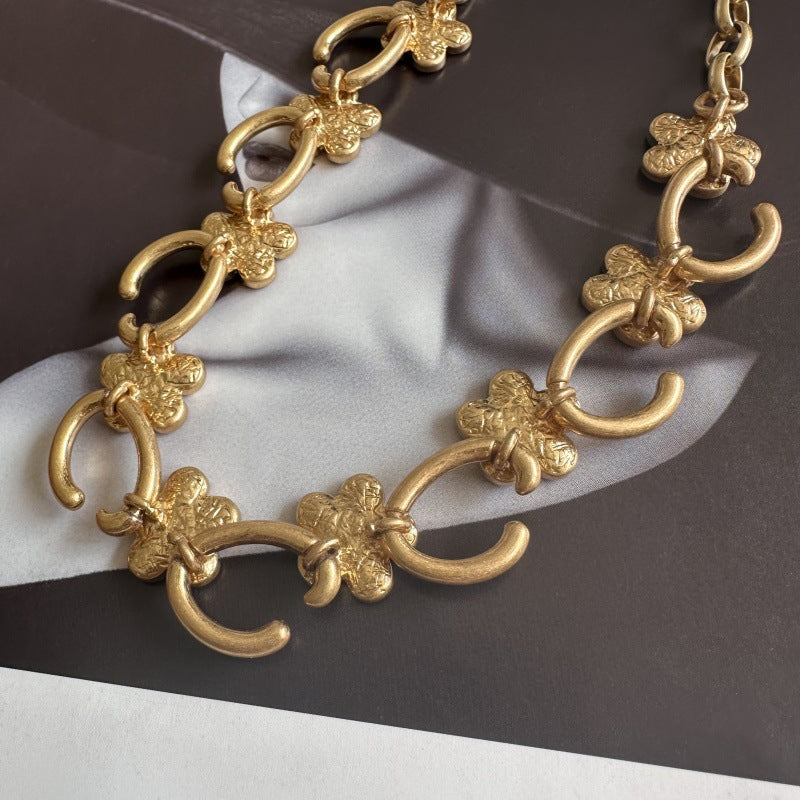 Close-up gold-tone floral O-ring necklace with sculpted flower charms and loop links
