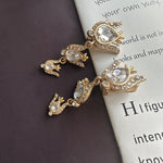 Gold-tone floral zircon drop earrings with clear oval stones and chain links