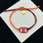 Pulsera con cordón naranja y burdeos ajustable, dije esmaltado rosa con marco dorado