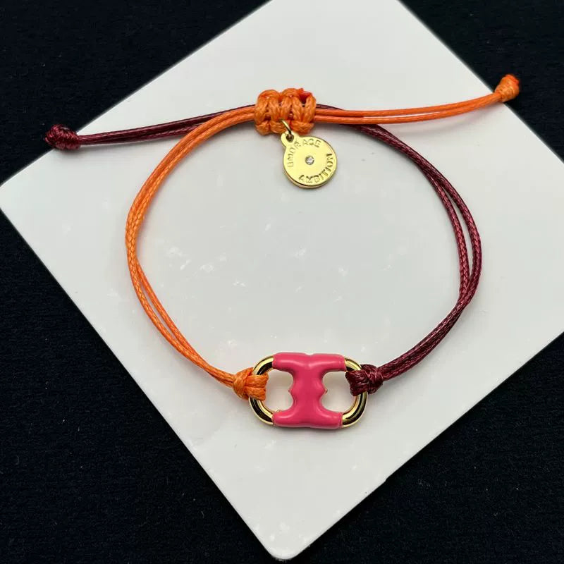 Pulsera con cordón naranja y burdeos ajustable, dije esmaltado rosa con marco dorado