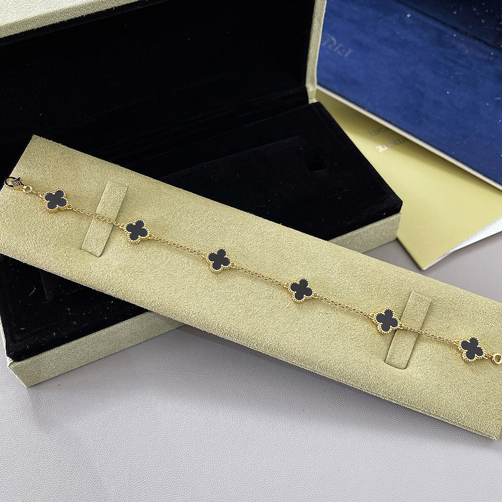 Gold tone bracelet with black clover charms and small chain links, four-leaf design