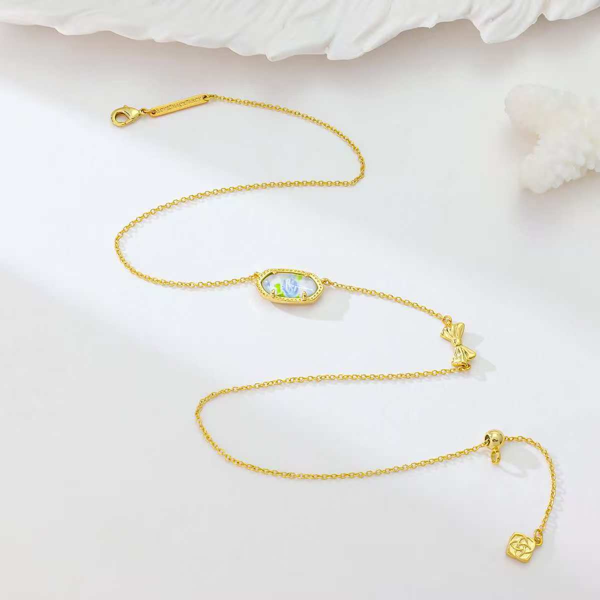Gold bow pendant necklace with blue rose-print oval centerpiece