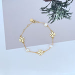 Gold-toned bracelet with pearl drops and interlocking puzzle-style charm links