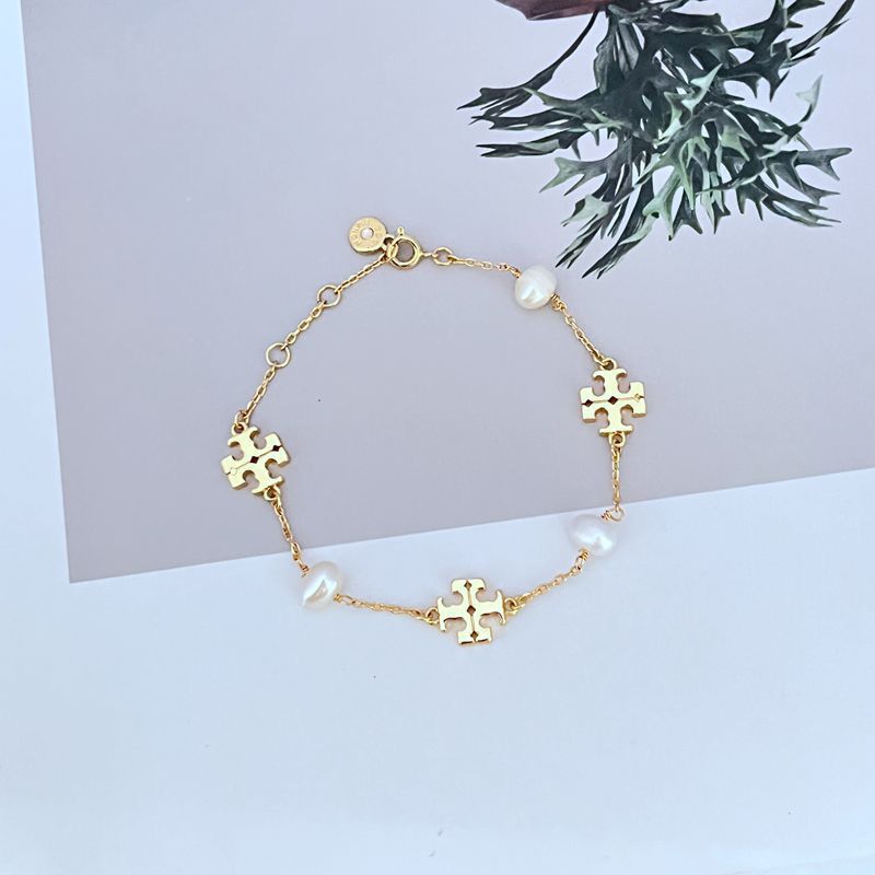 Gold-toned bracelet with pearl drops and interlocking puzzle-style charm links