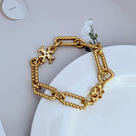 Gold square-logo chain bracelet with chunky links and layered charm accents