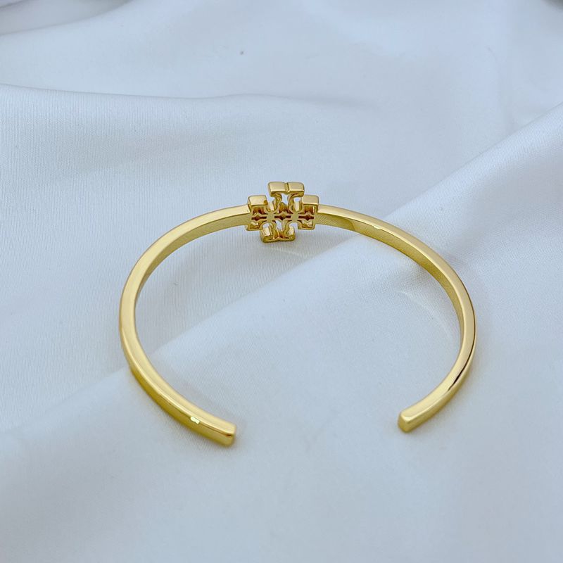 Gold open metal cuff bangle with square logo at top center