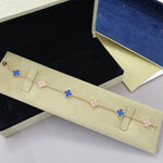 Goldfarbenes Armband mit abwechselnden Kleeblatt-Motiven in Blau und Rosa, mit Verschluss
