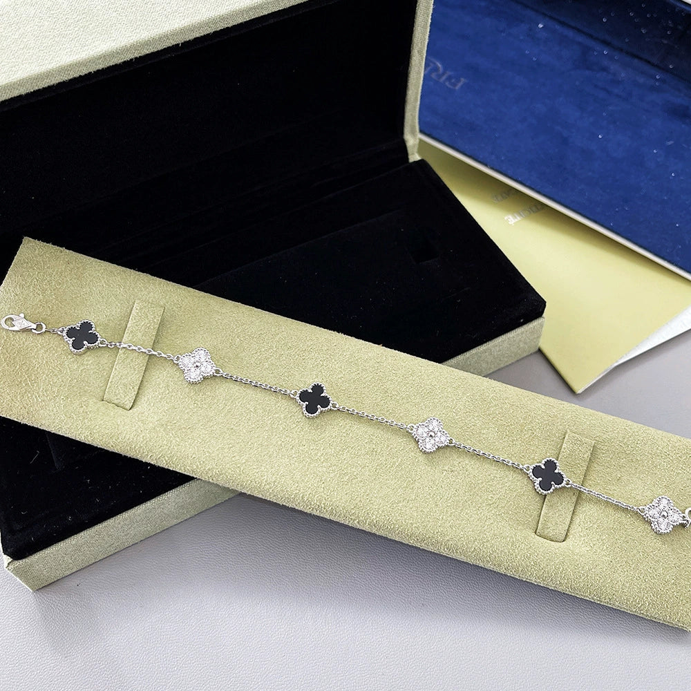 Goldfarbenes Armband mit schwarzen Vierblatt-Anhängern und silbernen Glitzer-Gliedern