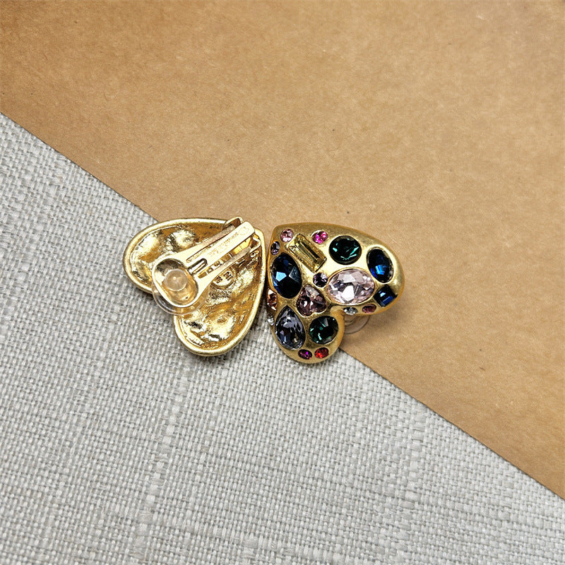 Heart-shaped crystal stud earrings, gold tone; side view shows butterfly back and stones