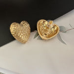 Gold textured heart stud earrings with visible post backs
