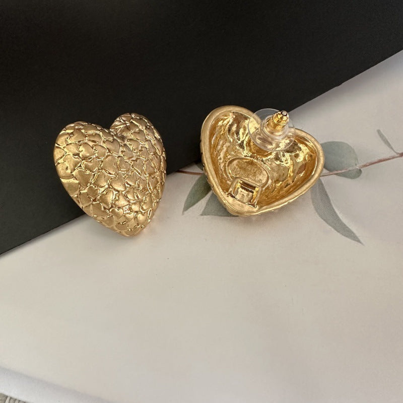 Gold textured heart stud earrings with visible post backs