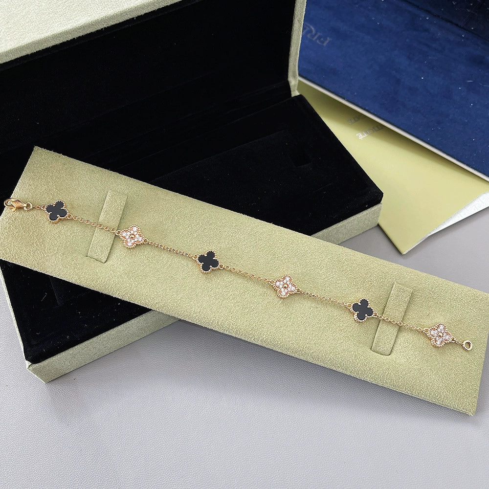 Goldfarbenes Armband mit schwarzen Vierblatt-Anhängern und roségoldfarbenen Glitzer-Gliedern