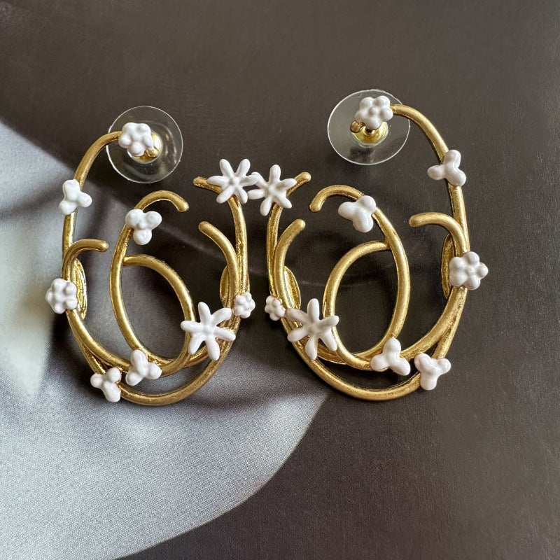 Gold hoop earrings with white enamel clover and snowflake accents