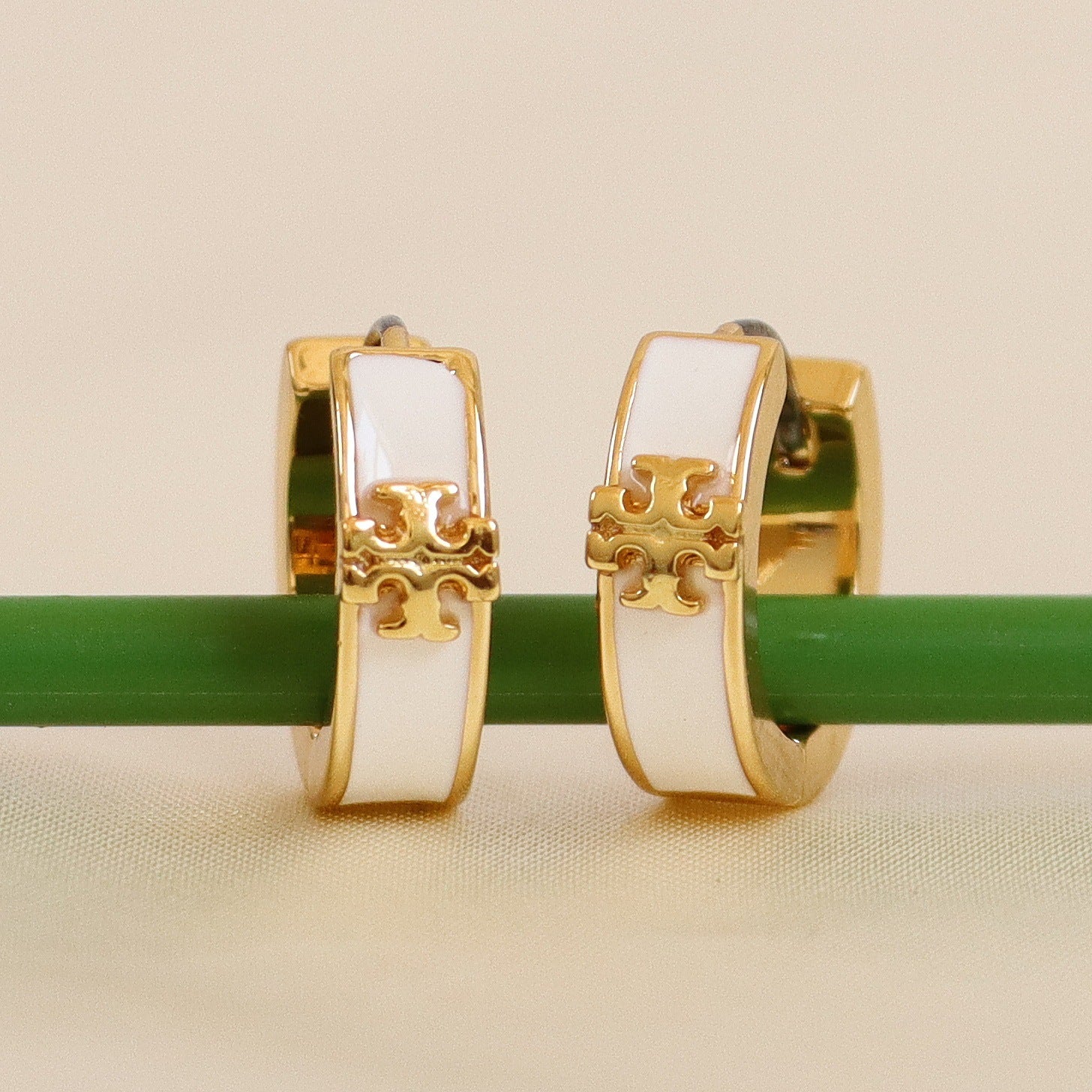 Enamel logo metal hoop earrings with white enamel panels and gold-tone hardware