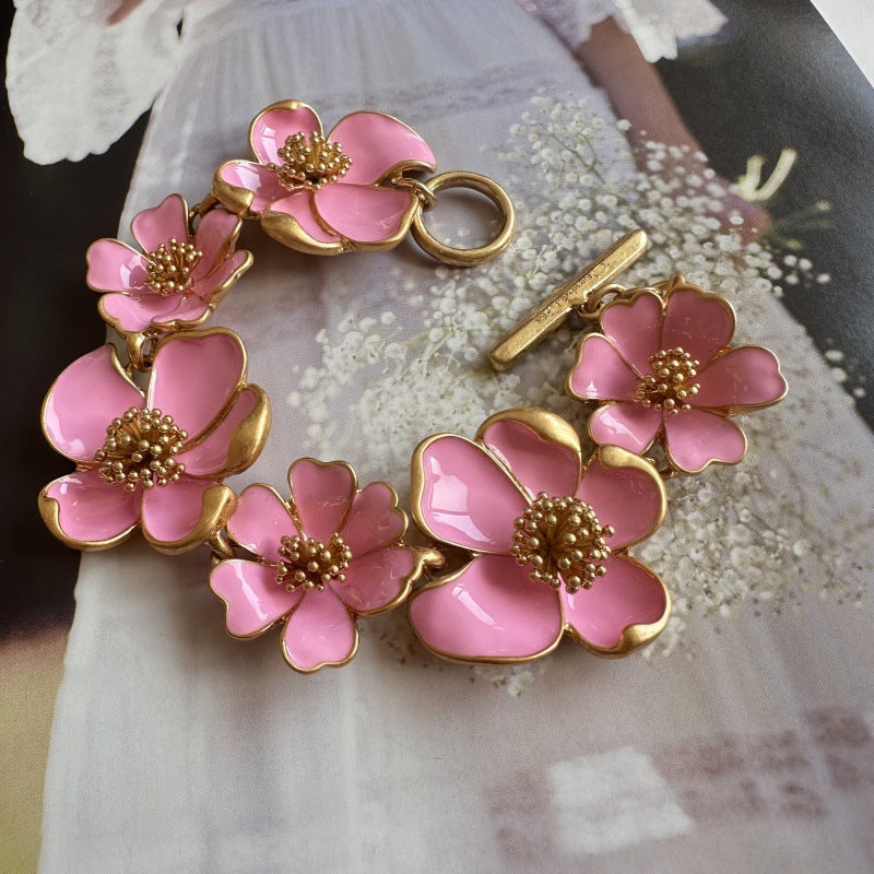 Enamel floral bracelet with gold-tone chain, pink petals, and raised bead flower details