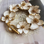 Intricate enamel floral bracelet with gold-tone chain, white petals and bead centers