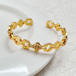 Gold tone clover openwork bangle with geometric links and small red enamel accents