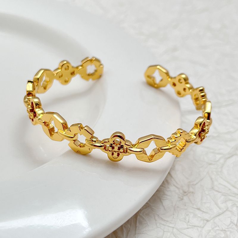 Gold tone clover openwork bangle with geometric links and small red enamel accents