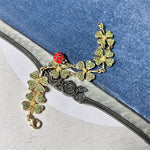 Gold-tone ladybug and four-leaf clover charm bracelet with dangling flower chain links