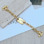 Gold chain bracelet/necklace close-up of engraved rectangular tag and H charm