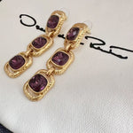 Purple crystal long drop clip-on earrings with three faceted oval stones in gold-tone frames