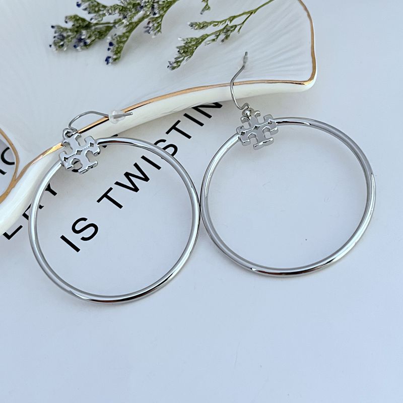 Large round silver hoop earrings with quatrefoil charm and hook closure