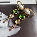 Long crystal drop earrings with gold frames, green stones, and pink crystal drops