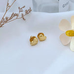 Gold heart-shaped matte metal stud earrings, backs and posts visible