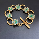 Türkisfarbenes Blumenarmband mit goldfarbenen Haken und funkelnden Steinen sowie Stabverschluss