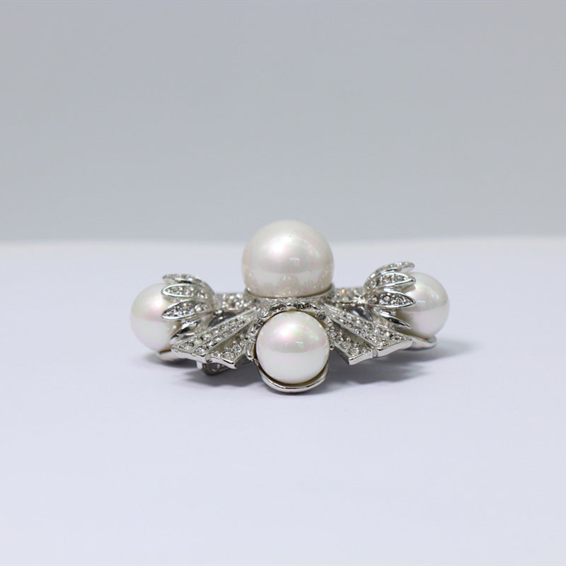 White-gold tone pearl and crystal brooch, round pearl center with four curved pearls