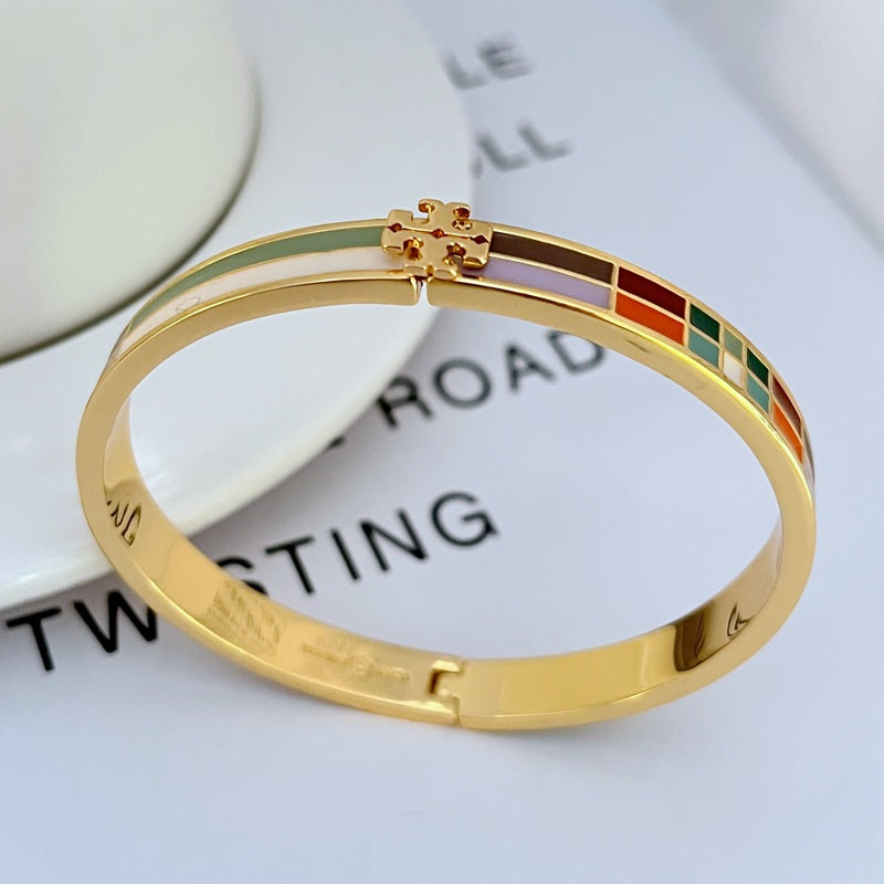Gold-tone bangle with multicolor enamel plaid stripe panels and decorative hinge clasp