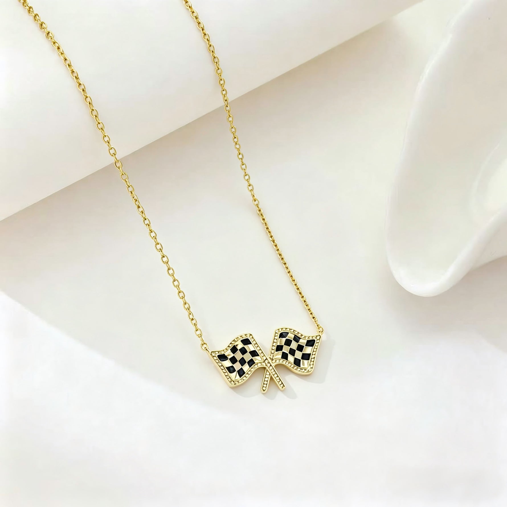 Gold chain necklace with checkered flag bow pendant at center