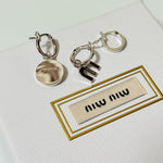 Three-piece enamel hoop earrings with round charm and letter logo charms in silver tone